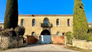 Un bâtiment en pierre avec une entrée centrale, des fenêtres en arc de cercle et un balcon.