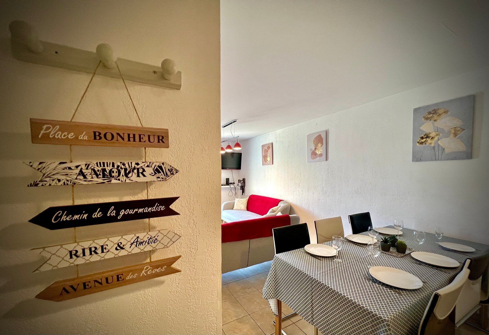 Ein Essbereich mit einem Tisch für vier Personen, einem roten Sofa und Wandbildern.