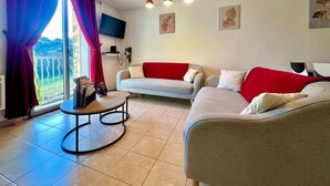 Un salon avec un canapé, une table basse, un téléviseur et une vue sur le balcon.