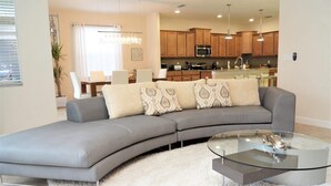 A modern living room with a grey sectional sofa, a glass coffee table, and a white shag rug.
