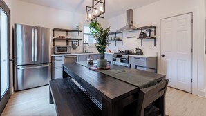 Una cucina moderna con elettrodomestici in acciaio inossidabile, un tavolo da pranzo in legno e una lampada a sospensione.