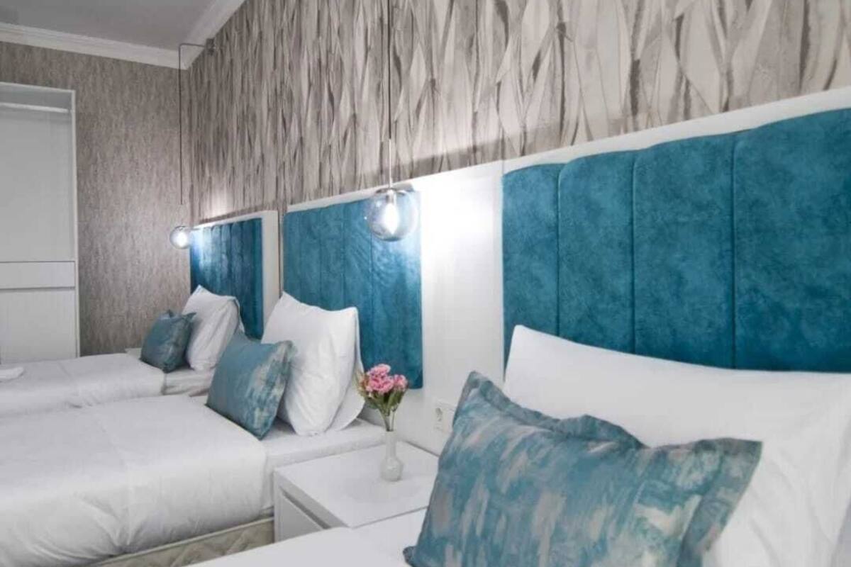 A hotel room with two beds, a marble-patterned wall, and a blue headboard.