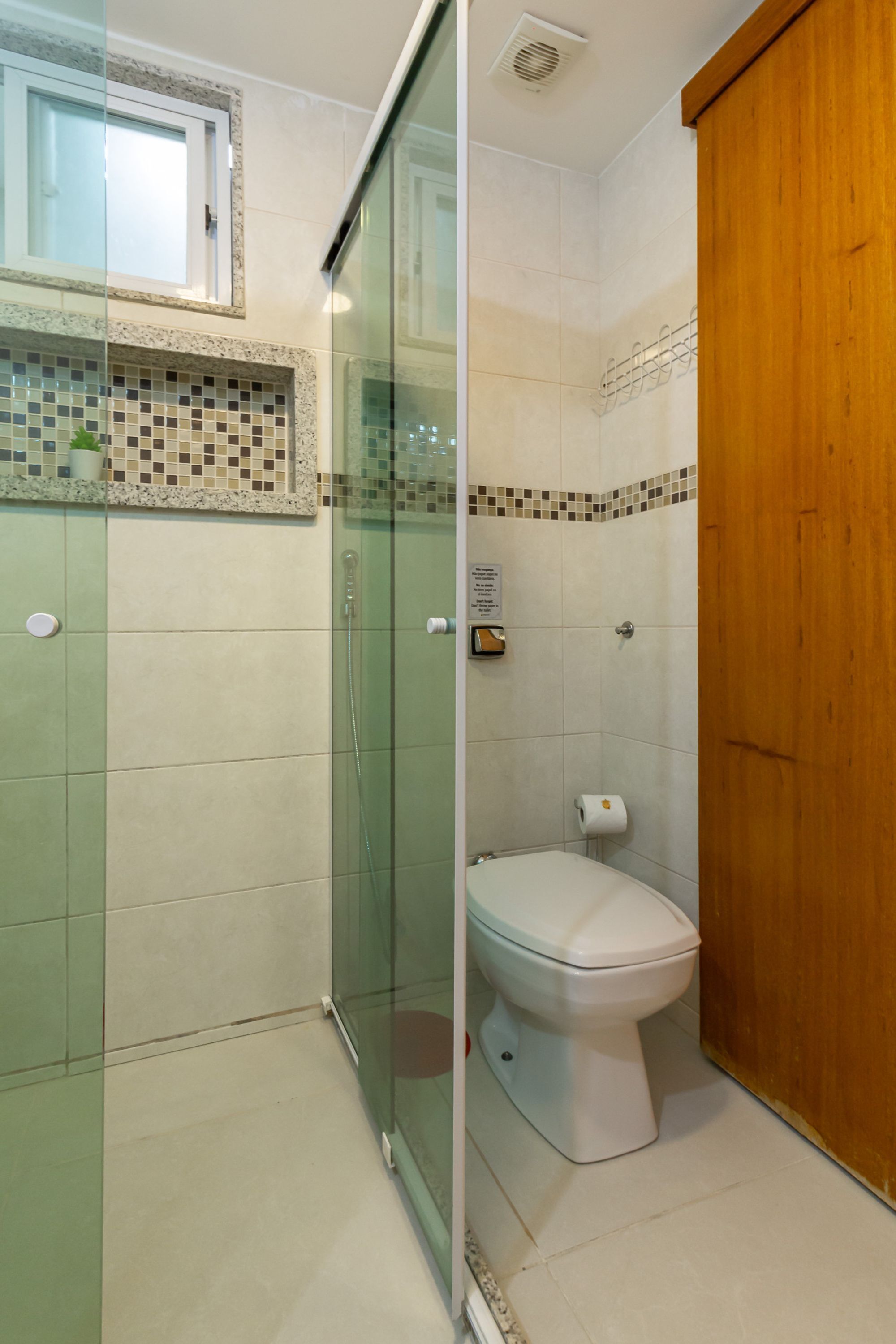 A bathroom with a glass-enclosed shower, a toilet, and a wooden door.