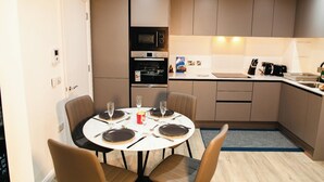 A compact kitchen with modern appliances, a dining area with four chairs, and a small island.