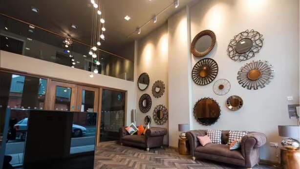 A modern lobby with two sofas, a coffee table, and decorative wall mirrors.