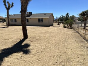 Situated in a dry, open area, this single-story house features a flat roof and a metal fence.