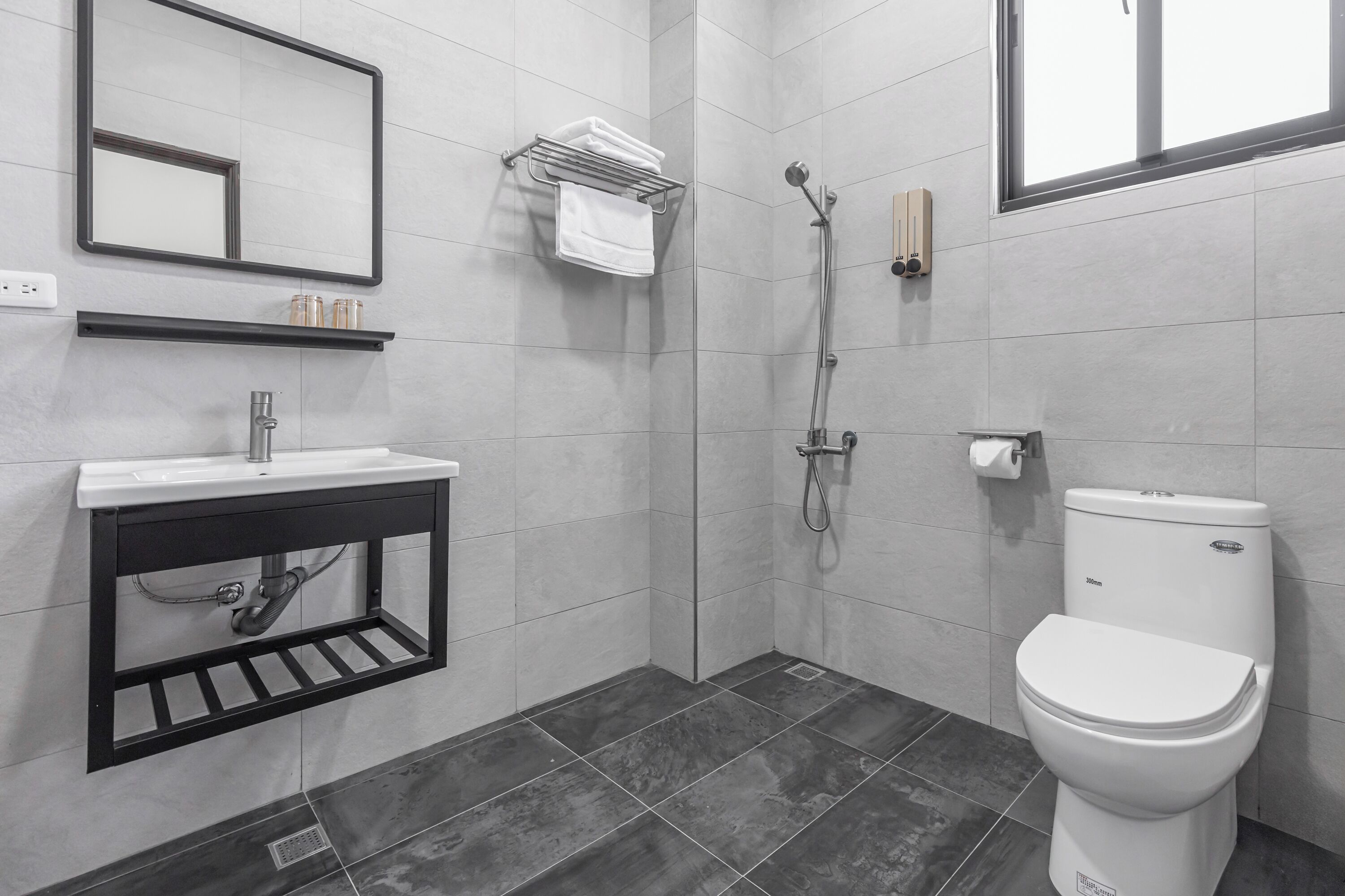 Un baño moderno con un lavabo blanco, lavamanos negro, un inodoro y una ducha.