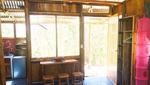 Eine Holzjagdhuette mit Küchenbereich, einem Esstisch mit Hocker und einem großen Fenster.