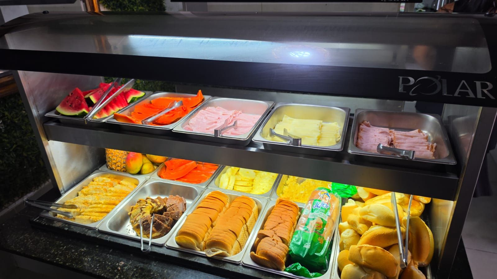 A buffet with various food items including meats, fruits, and pastries.