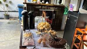 Una mesa de buffet con diversos alimentos, una estación de café y una zona de estar con sillas.