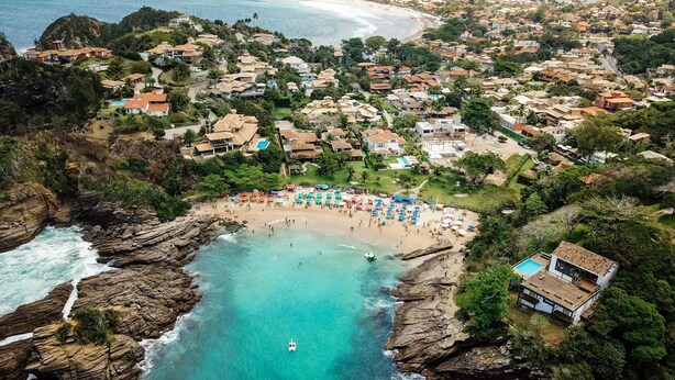 Vista aérea de un pueblo costero con playa, costa rocosa y edificios residenciales.