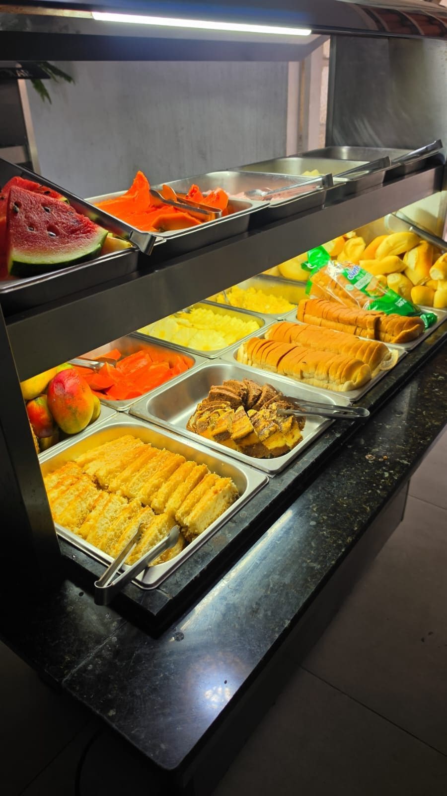 Un bufé con diversos alimentos, incluyendo frutas, pan y pastelería.