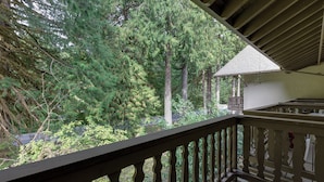 A balcony with a view of a forested area and a small white building with a sloped roof. - Mt Baker Lodging Condo - Perfect for Smaller Families on the Go (Deming)