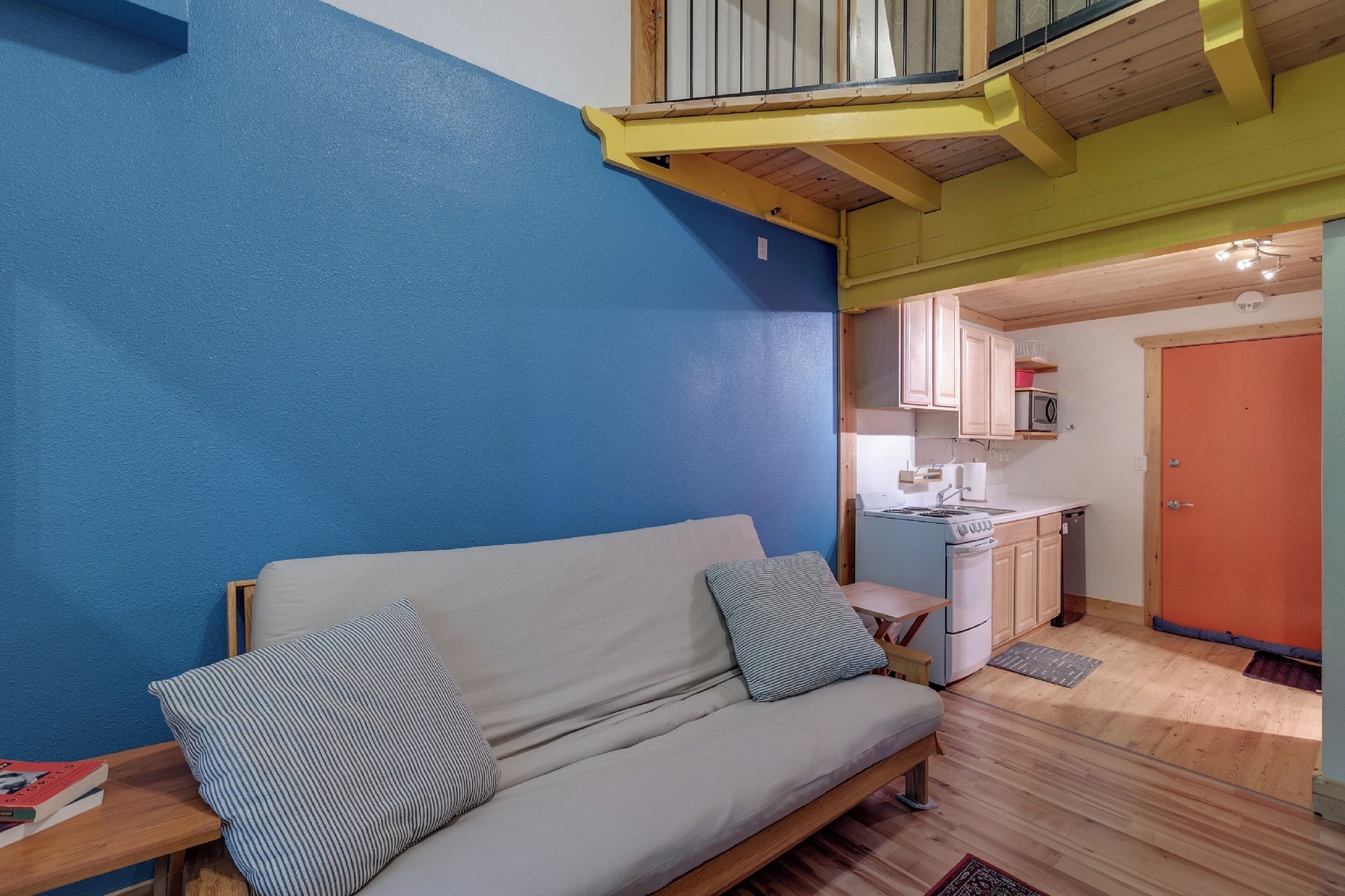 Un espacio habitable compacto con sofá, una pequeña cocina y un balcón.