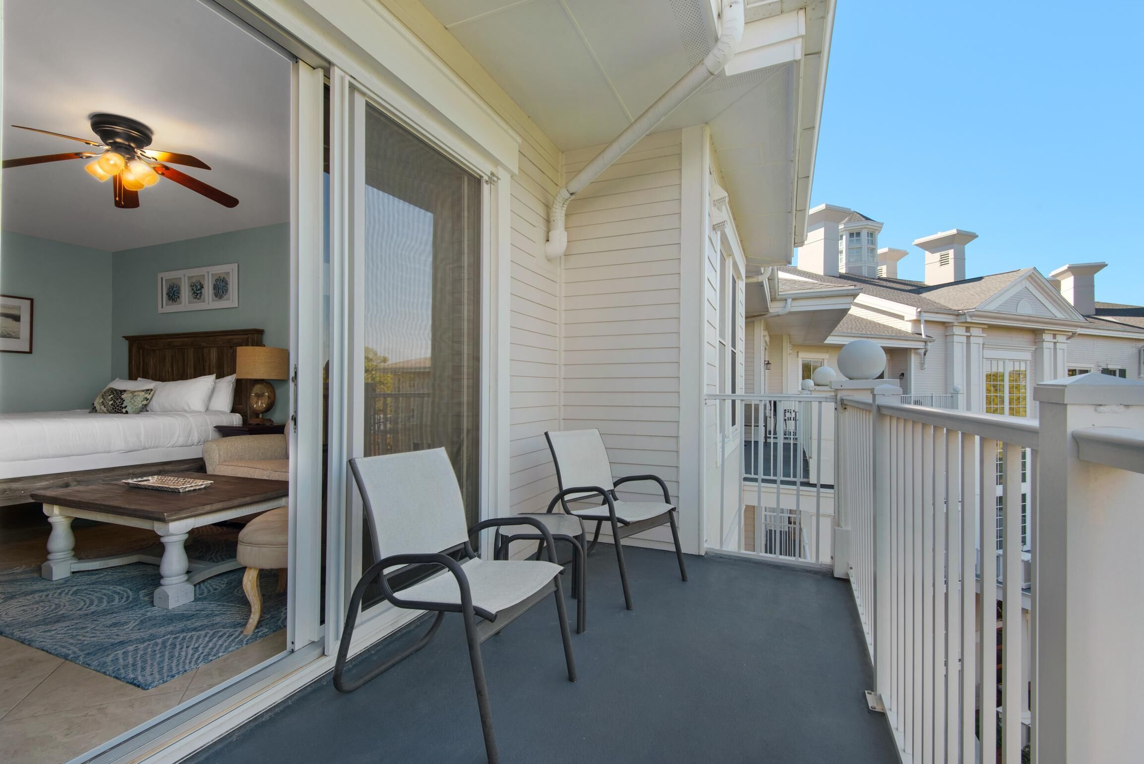A balcony with a ceiling fan, a sofa, a coffee table, and two chairs.