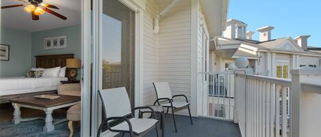 A balcony with a ceiling fan, a sofa, a coffee table, and two chairs.