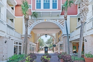 Uma galeria coberta com uma placa indicando 'The Village of Baytowne Wharf' e palmeiras.