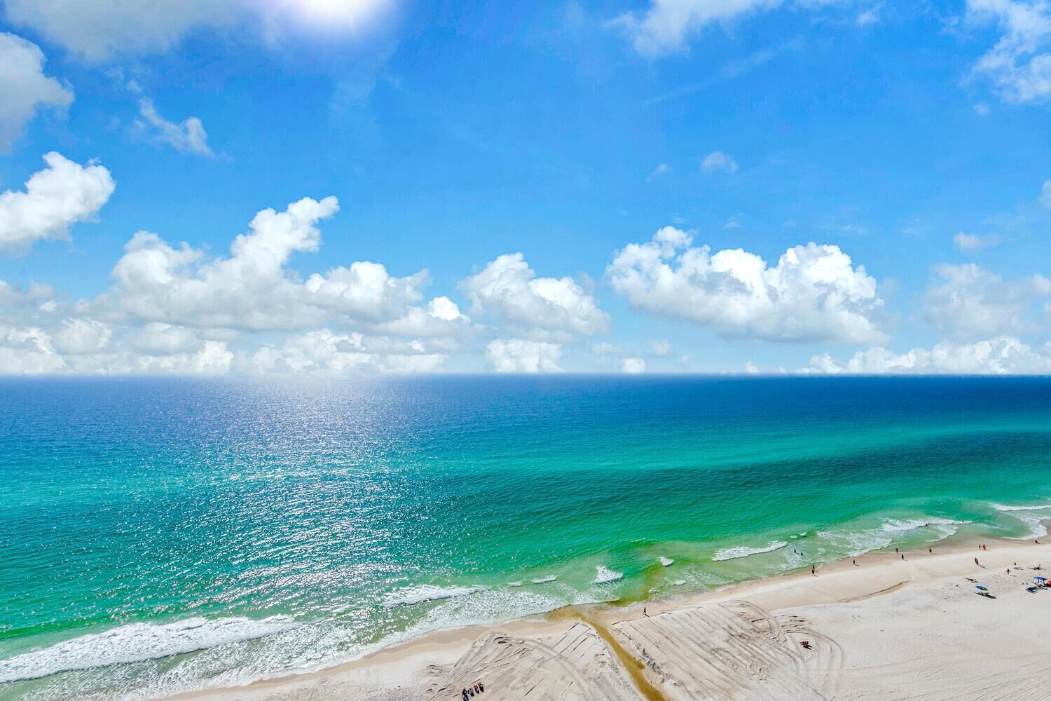 Una playa con aguas turquesas cristalinas, una orilla arenosa y cielo despejado.