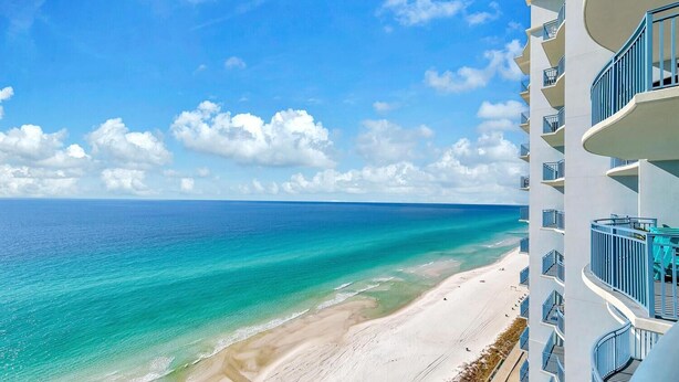 A high-rise hotel with balconies overlooking a beach and the ocean.