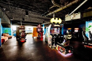 A gaming area with arcade machines, a couch, and a view of the outdoors.