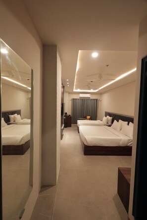 A hotel room with two beds, a mirror, a desk, and a view of the hallway. - Nirvana Boutique Hotel (Ujjain)