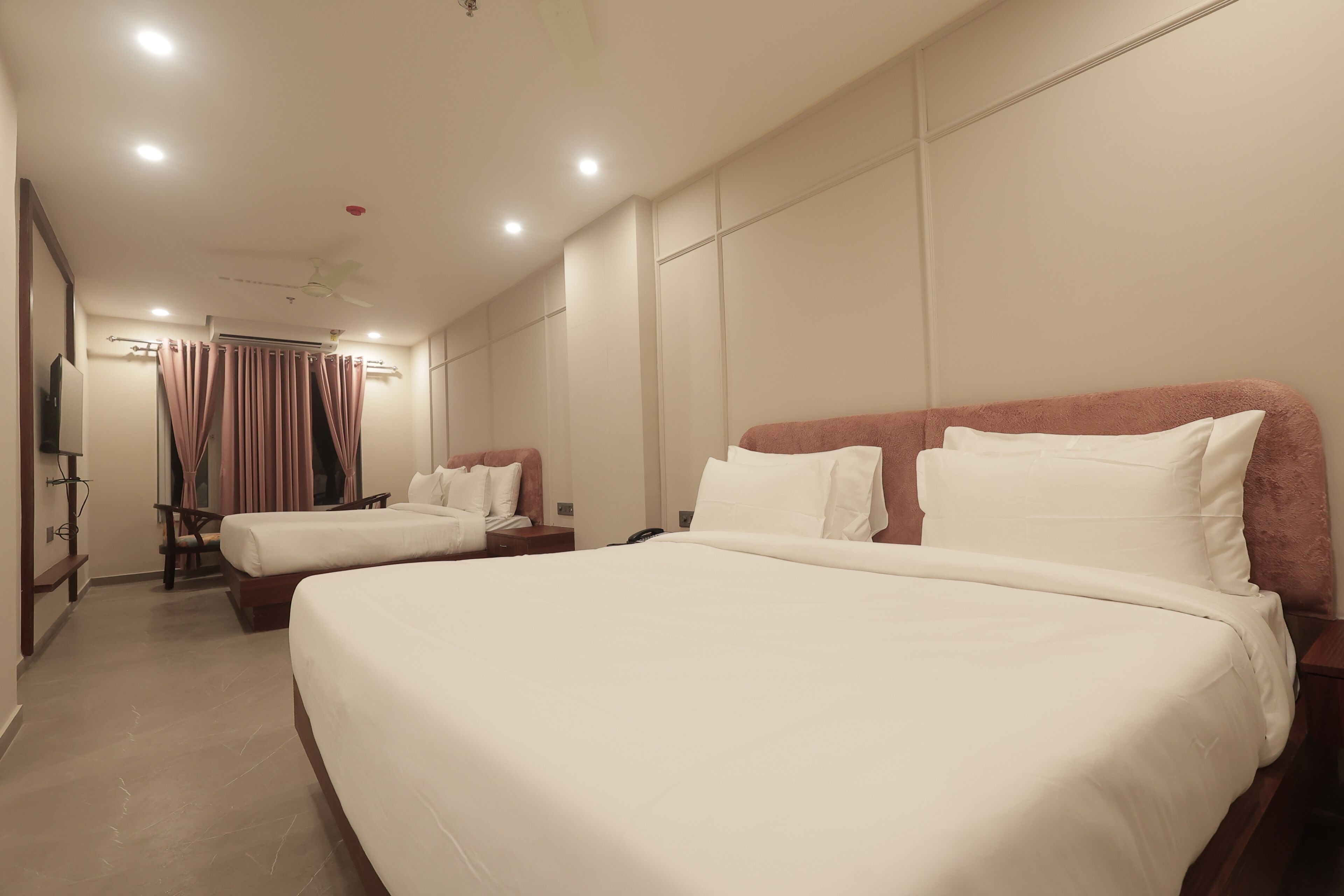Une chambre d’hôtel avec deux lits, un bureau, une chaise et un ventilateur de plafond.