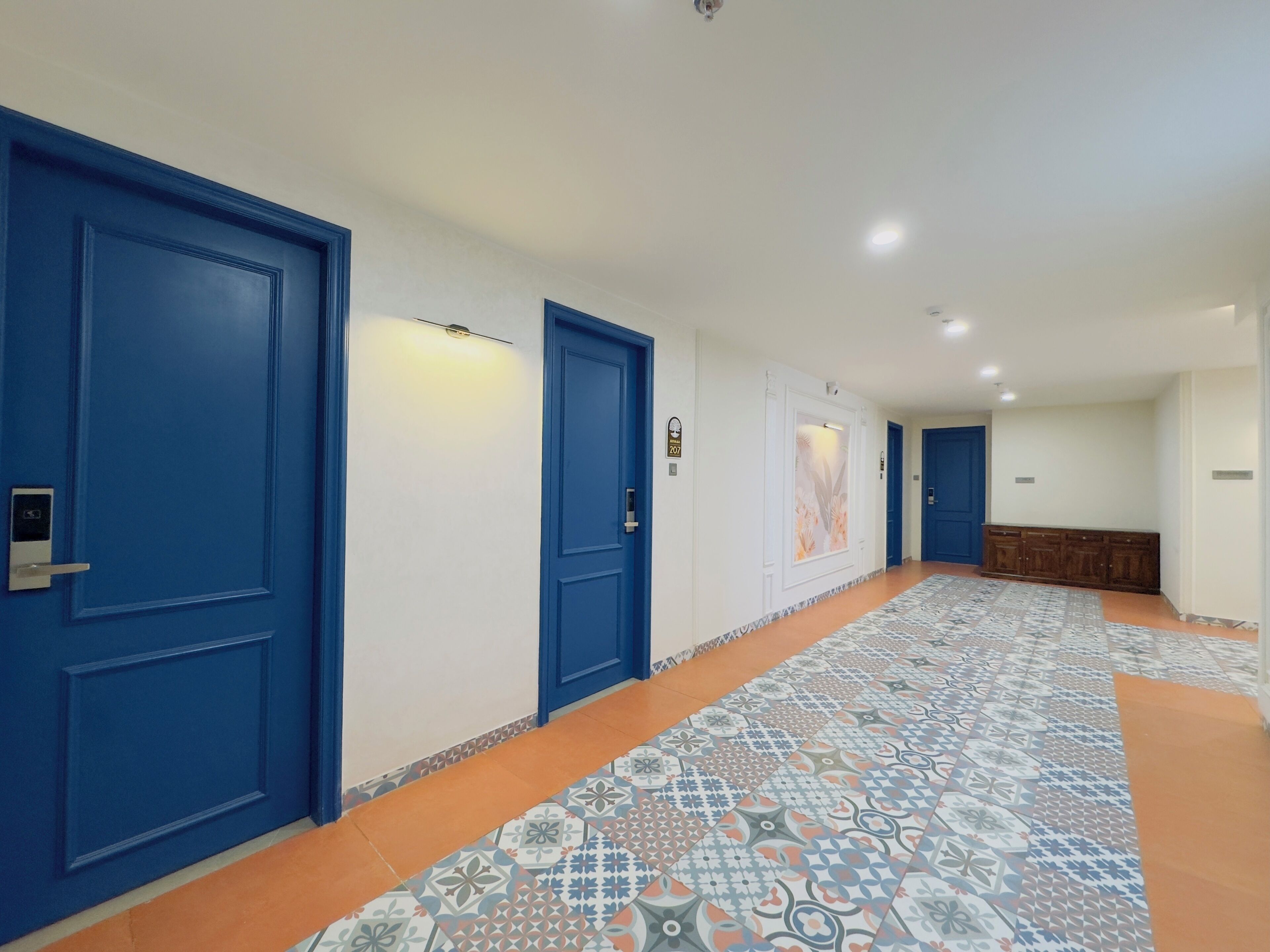 A hallway with blue doors, patterned floor tiles, and a wooden bench.