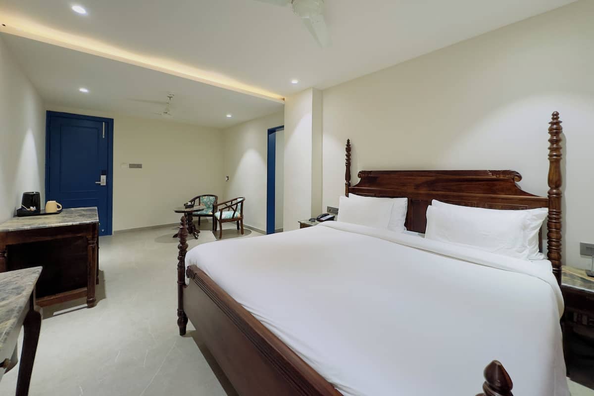 Une chambre d’hôtel avec un grand lit, un bureau, une chaise et une porte bleue.