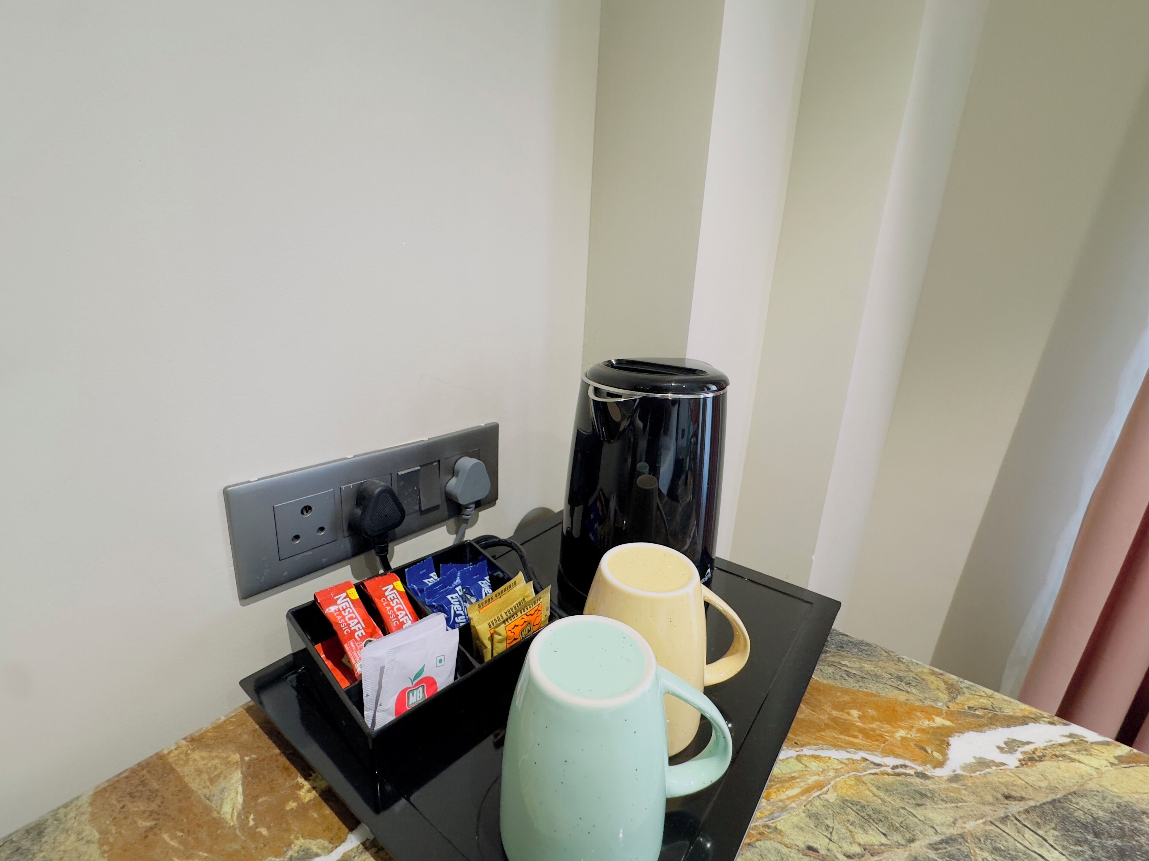 A coffee station with a coffee maker, a mug, and a box of coffee pods.