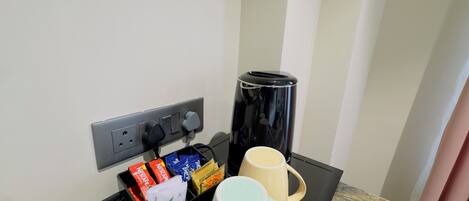 A coffee station with a coffee maker, a mug, and a box of coffee pods.