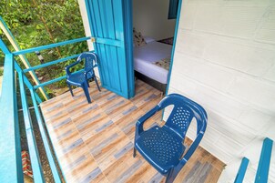 Una habitación con una cama, una silla azul y suelo de madera.