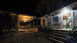 A building with a covered outdoor seating area, steps leading to the entrance, and hanging plants. - La Posada De Las Aves (San Rafael)