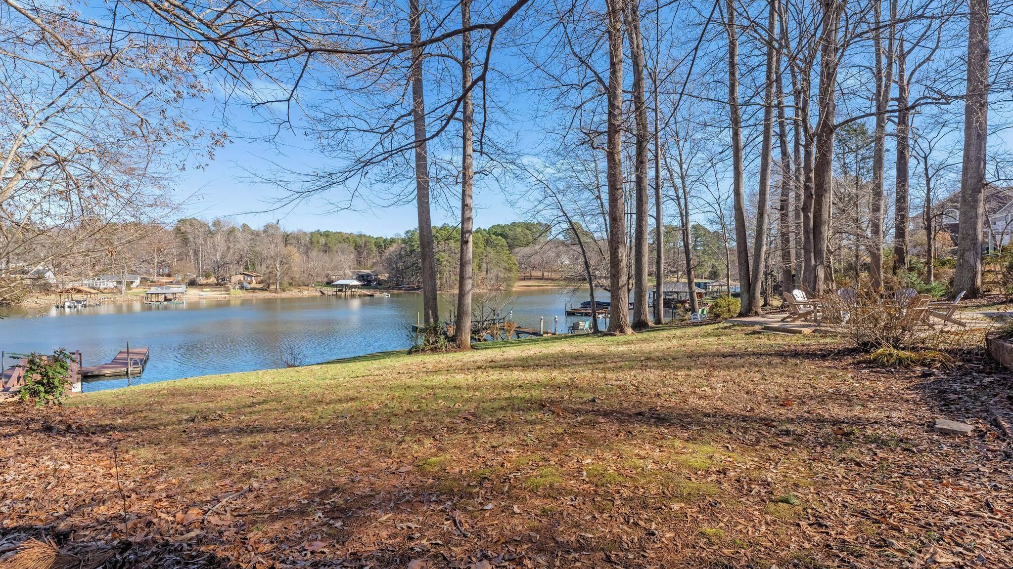 A lakeside view with docked boats, a grassy area, and trees.