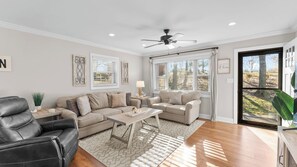 A living room with a sofa set, a coffee table, a floor lamp, and a ceiling fan.