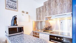 A compact kitchen with a microwave, stove, and sink. - Les Lupins - Station de ski à pied (Eyne)