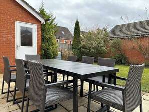 Un patio al aire libre con una mesa rectangular y seis sillas.