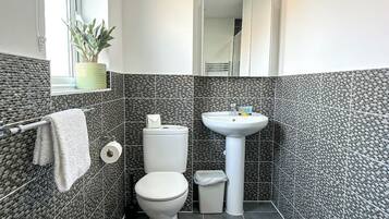 A bathroom with a toilet, sink, and a towel rack.