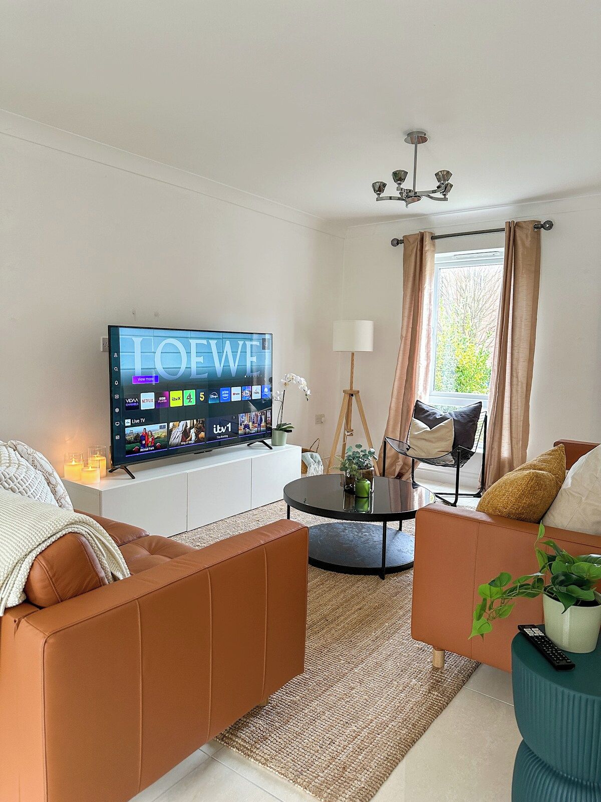 A modern living room with a flat-screen TV, a sofa, a coffee table, and a lamp.