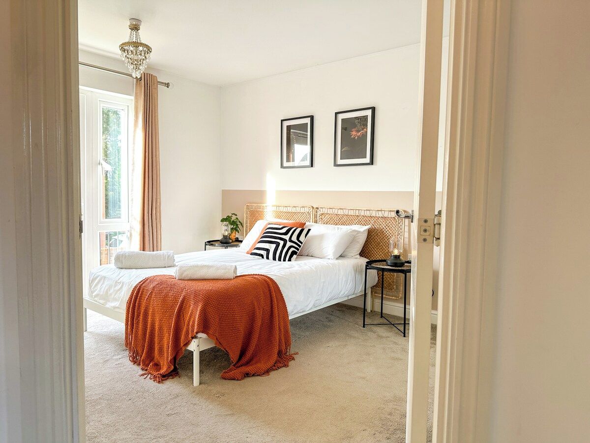 A bedroom with a bed, bedside table, and a window with curtains.