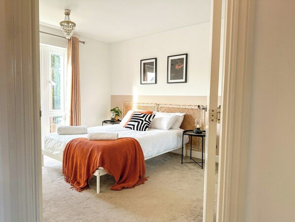 Un dormitorio con cama, mesita de noche y ventana con cortinas.