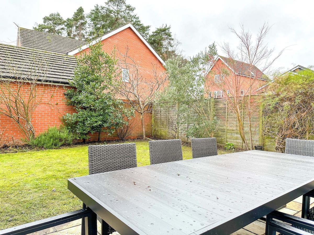 A patio with a table and chairs, surrounded by a brick wall and trees.