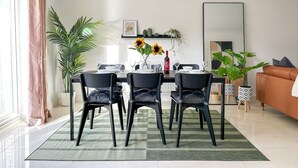 A modern dining area with a round table, black chairs, and a chandelier.