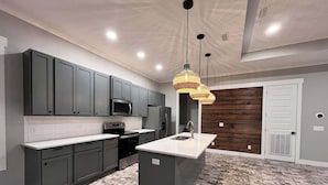 A modern kitchen with grey cabinets, a central island, and a patterned floor.