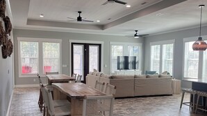 A spacious living area with a wooden dining table and chairs, a large sofa, and a ceiling fan.