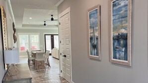 A hallway with a herringbone floor, white doors, and two framed paintings on the wall.