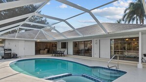 An indoor swimming pool with a glass ceiling, a barbecue area, and a patio with outdoor furniture. - Riverside Retreat: 4BR/3BA with Private Dock and Boat Lift (Stuart)