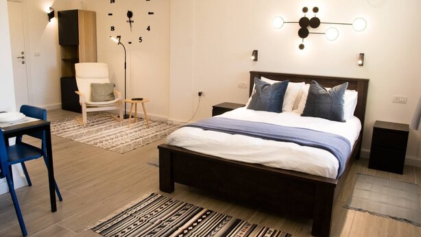 A modern bedroom with a large bed, bedside tables, a desk, and a chair.