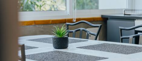A dining table with a potted plant, grey placemats, and chairs.