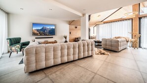 Un soggiorno moderno con un ampio divano componibile, una televisione fissata alla parete e un soffitto in legno.