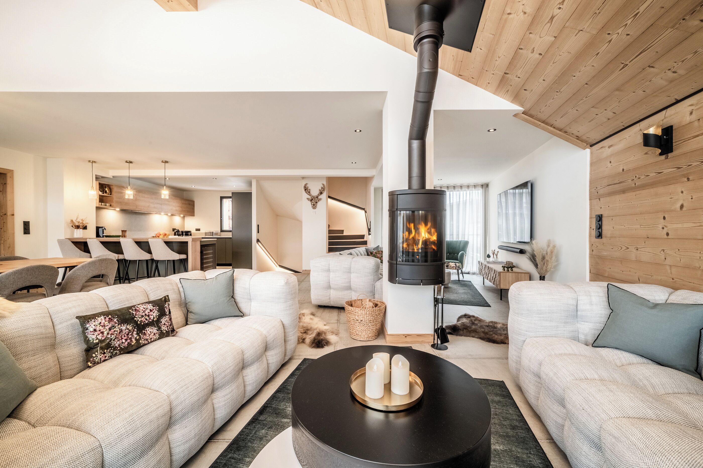 A modern living room with a central fireplace, a sofa set, and a dining area in the background.